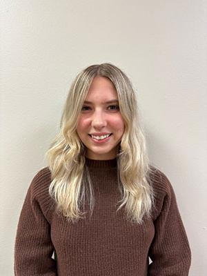 white woman with blonde hair wearing a brown sweater